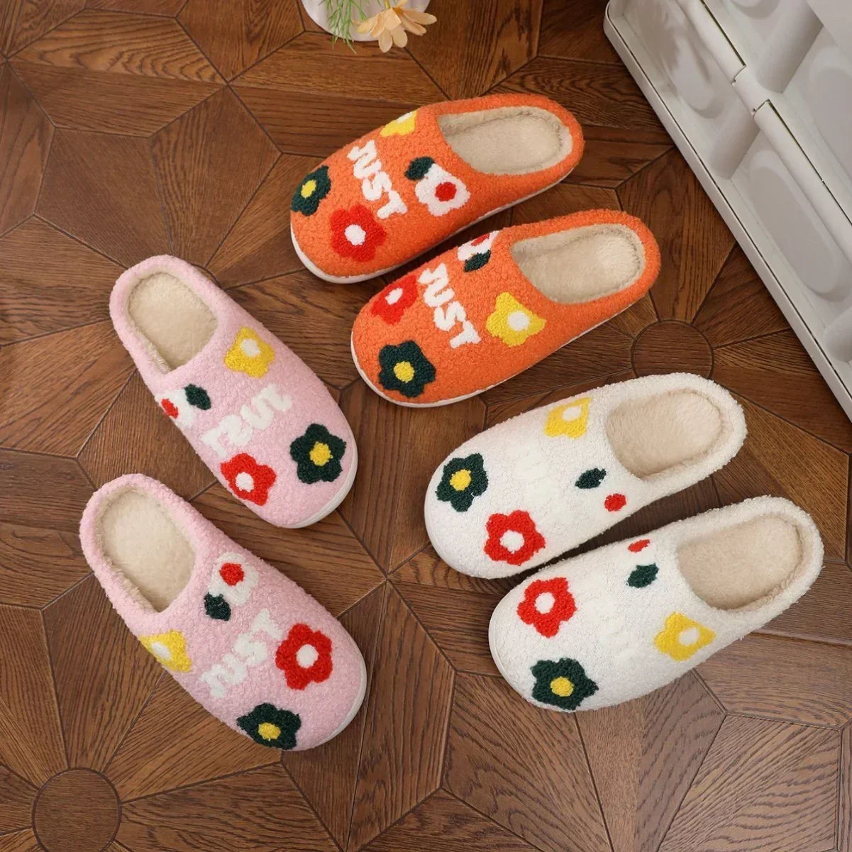 Cozy slip-on slippers in orange, pink, and white with floral patterns and plush material