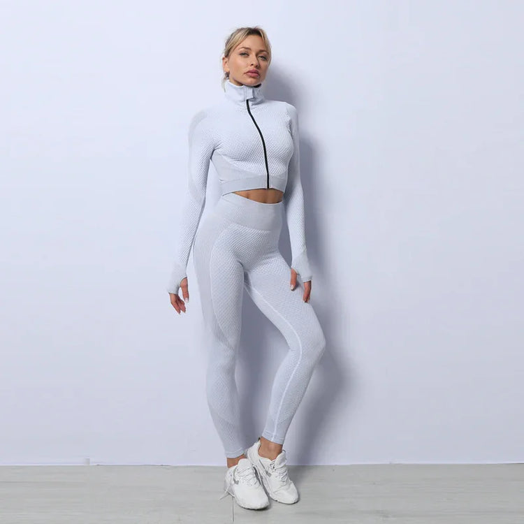 Woman in textured white fitted athleisure set with high-waist leggings and zip-up crop top
