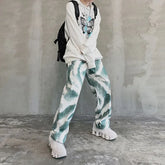 Oversized white hoodie with butterfly print, loose green and white patterned pants, chunky sneakers, streetwear style.