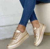 Beige metallic low-top sneakers with gold accents worn with skinny blue jeans