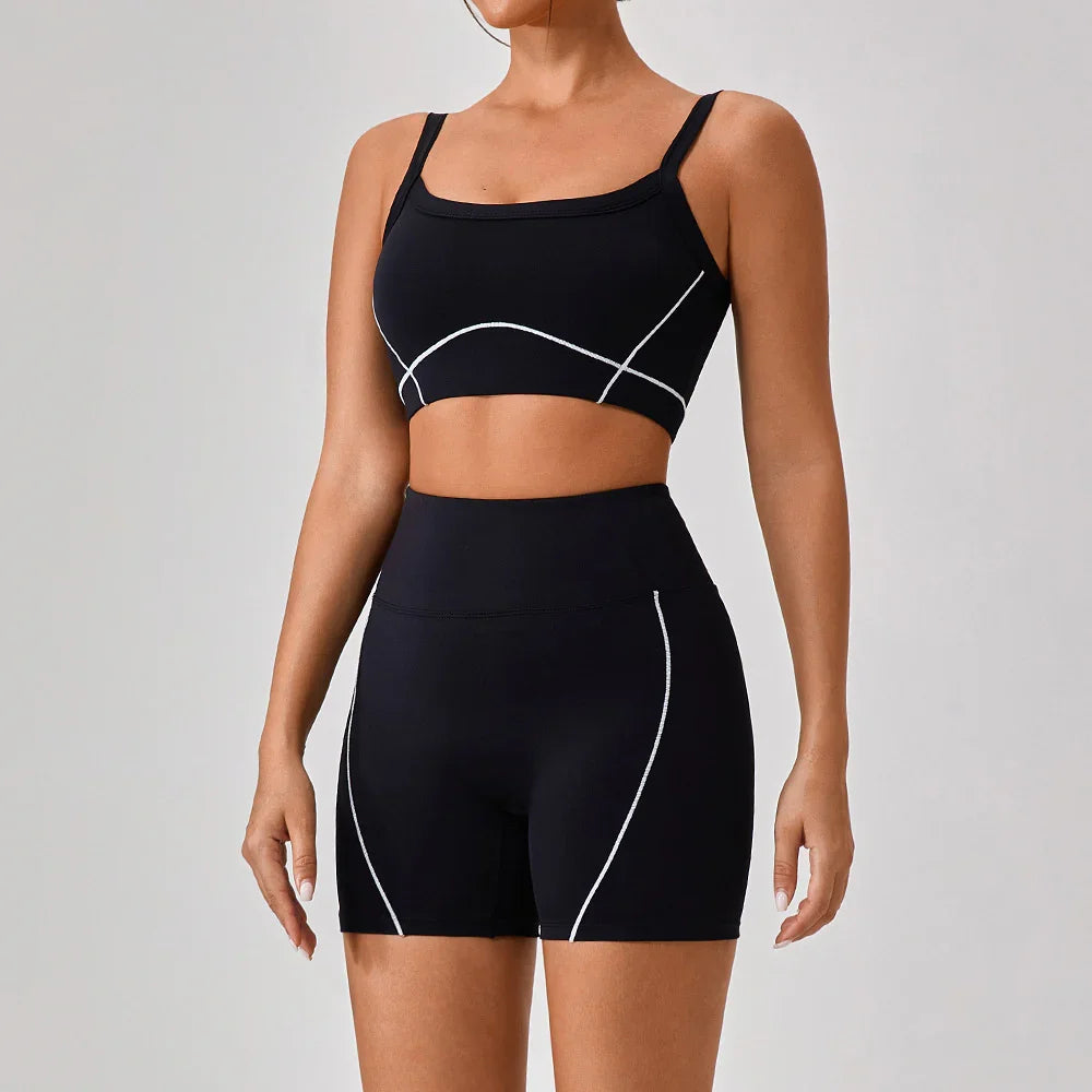 Woman wearing black fitted sports bra and high-waisted biker shorts with white seam detailing