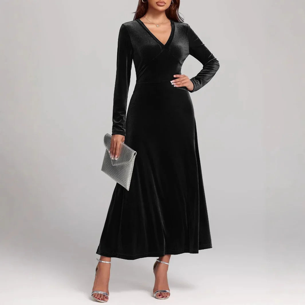 Woman wearing long black velvet A-line dress with V-neck and long sleeves, silver heels