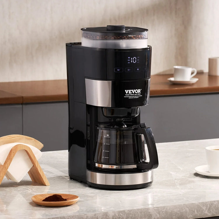 Modern black coffee maker with built-in grinder and glass carafe on a kitchen counter