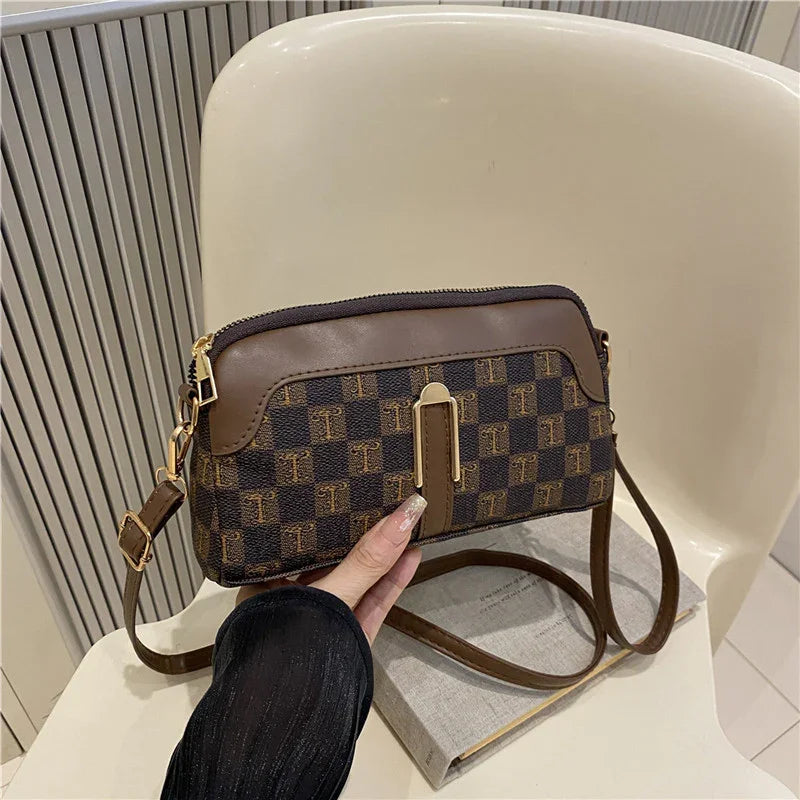 Brown checkered crossbody bag with gold hardware, faux leather trim, and adjustable strap