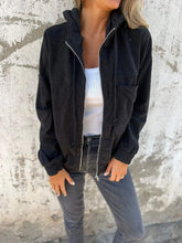Woman wearing black corduroy zip-up jacket, white ribbed tank top, and gray jeans, relaxed fit