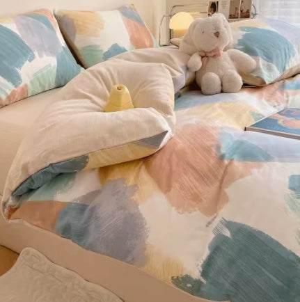 Pastel abstract print cotton bedding set with relaxed fit on a cozy bed, plush toy on top.