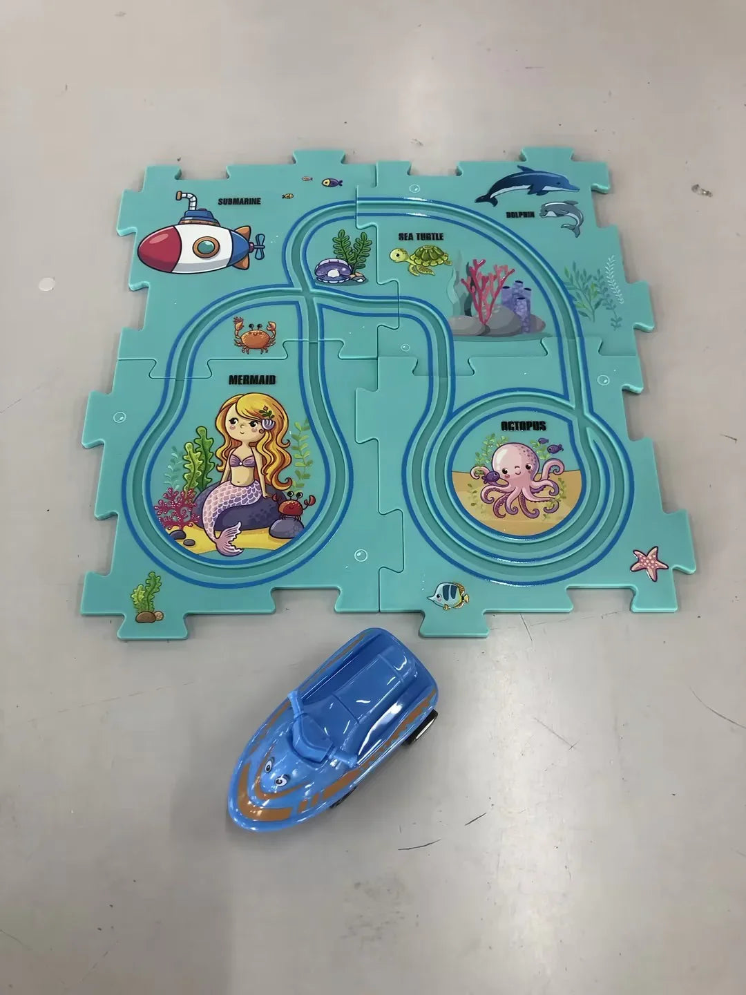 Colorful undersea-themed puzzle mat with cartoon mermaid, sea animals, and a blue toy boat.