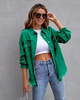 Woman in green oversized distressed denim jacket, white crop top, and high-waisted blue jeans
