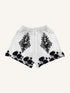 White streetwear shorts with black baroque portrait and floral rose patterns, relaxed fit