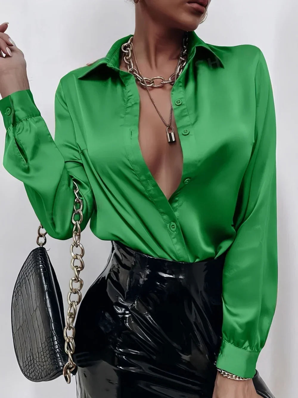 Woman wearing a shiny green satin blouse with a deep v-neck and a black patent leather skirt
