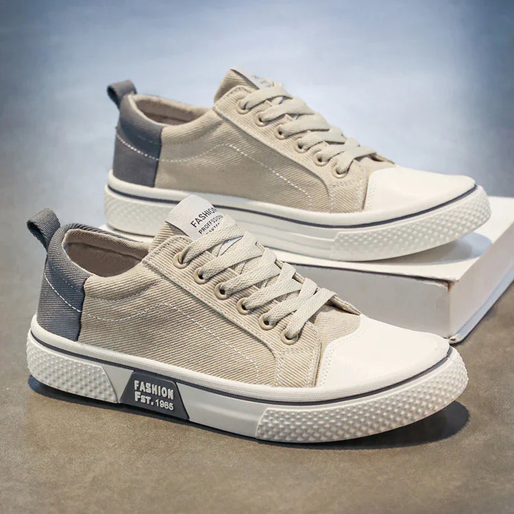 Beige canvas low-top sneakers with white rubber soles and gray accents, casual streetwear style