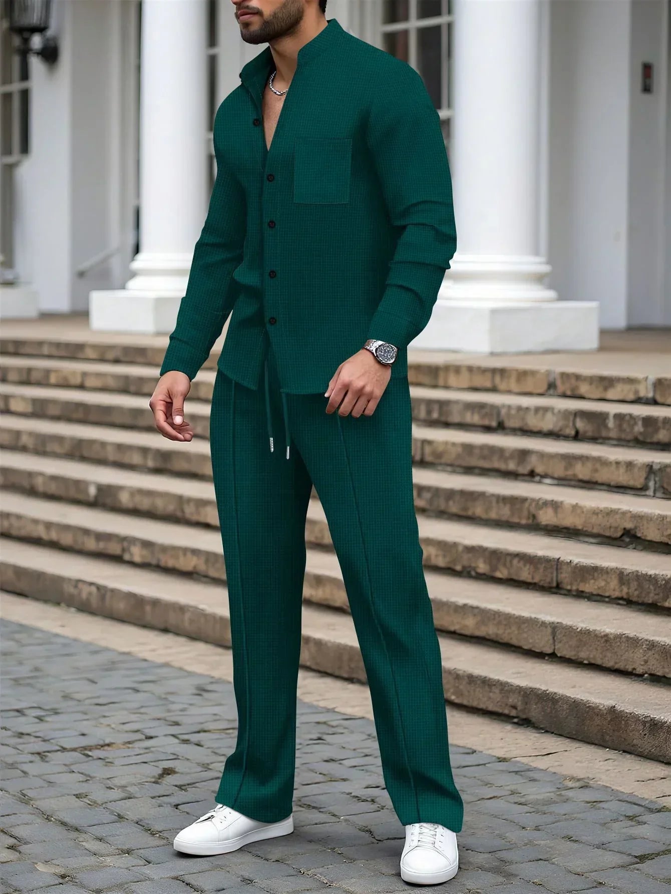 Man wearing dark green textured two-piece set with relaxed fit and white sneakers outdoors