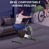 Woman in white sports bra and blue leggings using exercise bike indoors, fitted activewear