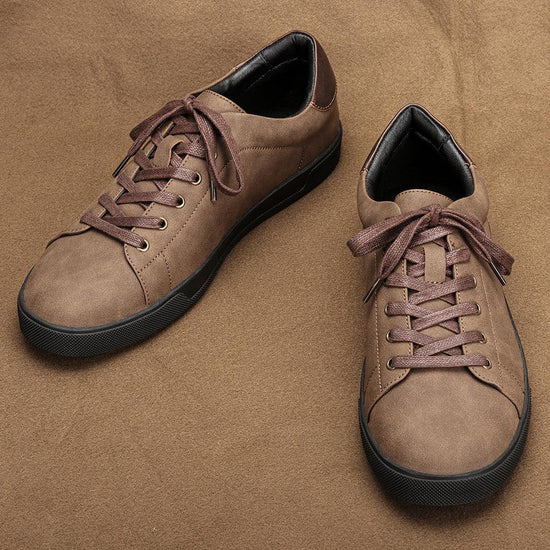 Brown faux leather low-top sneakers with round toe, lace-up closure, and black rubber sole