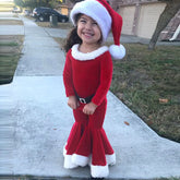 Smiling child in red velvet Santa dress with white faux fur trim and flared skirt outdoors