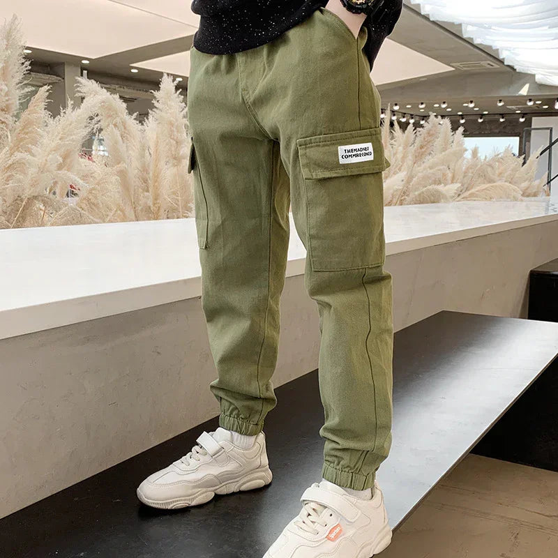 Olive green cargo jogger pants in cotton with relaxed fit and utility pockets, streetwear style