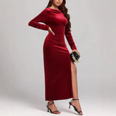 Woman in a fitted long-sleeve red velvet maxi dress with side slit and black heels