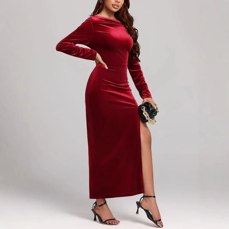 Woman in a fitted long-sleeve red velvet maxi dress with side slit and black heels