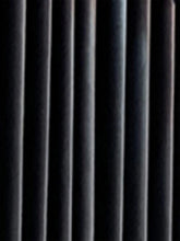 Close-up of black velvet curtain with soft vertical folds, rich texture, and matte finish