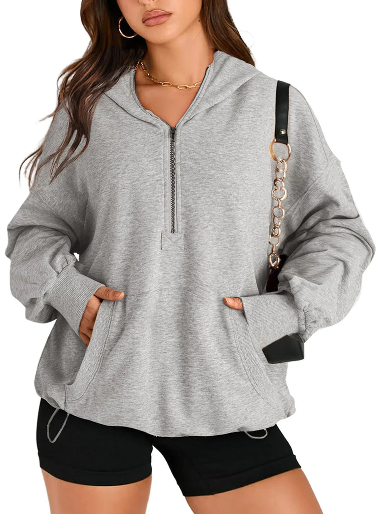 Woman wearing oversized light gray zip-up hoodie with kangaroo pocket and black shorts