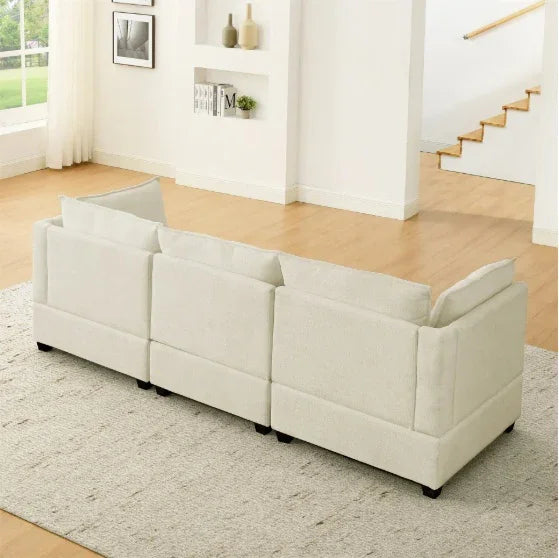 Back view of a modern off-white fabric sectional sofa with loose cushions in a bright living room