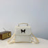 White faux leather mini backpack with black butterfly patch, top handle, adjustable straps