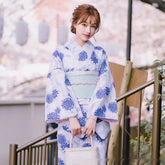 Woman wearing a light blue floral kimono with loose fit and wide sleeves, holding a white bag