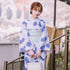 Woman wearing a light blue floral kimono with loose fit and wide sleeves, holding a white bag