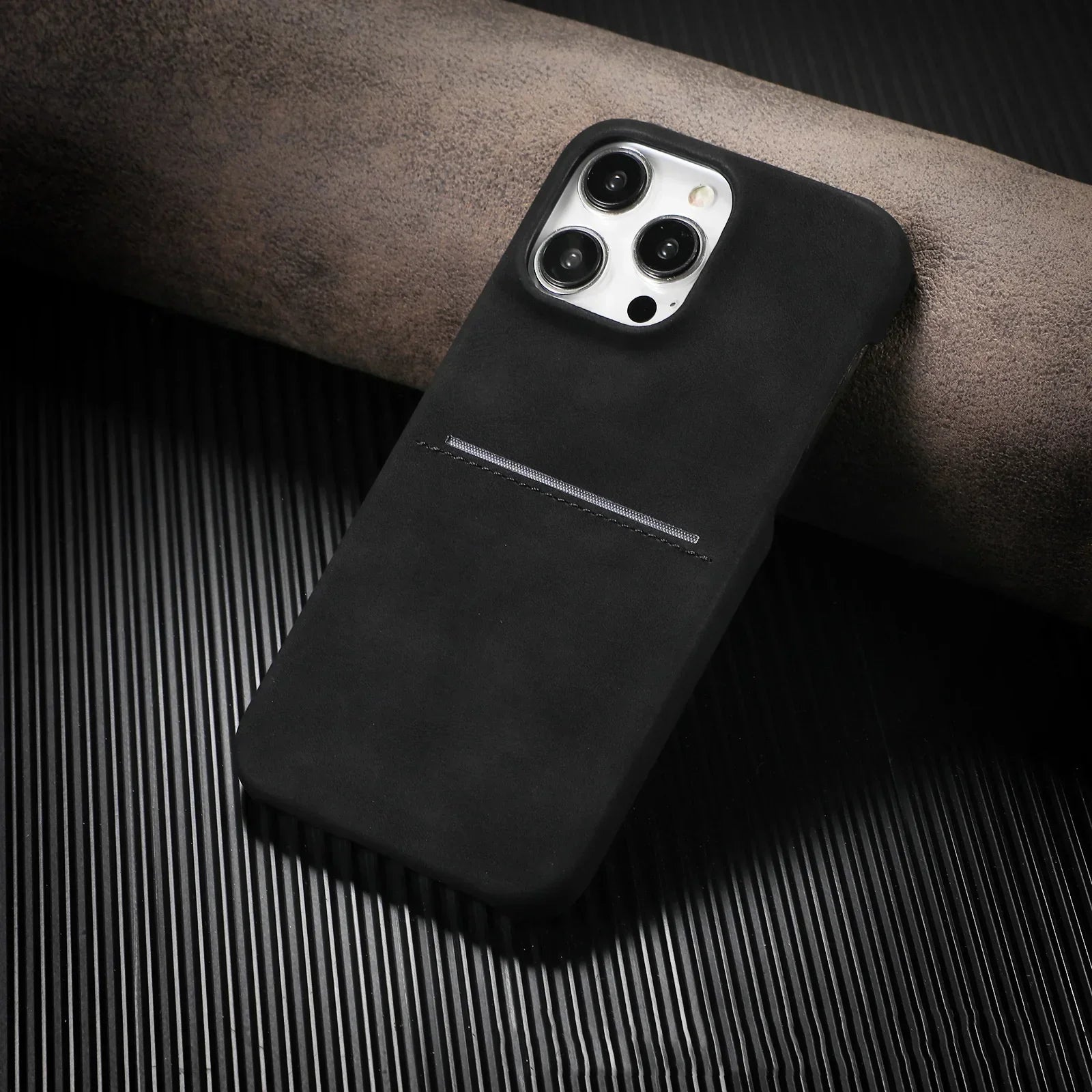 Black suede phone case with minimalist design and slim fit on a ribbed surface