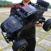 Person holding a large black off-road RC car with rugged tires and metallic details outdoors.