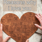 Heart-shaped wooden puzzle with engraved love messages, held by two hands on a rustic surface.