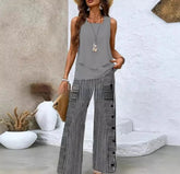 Woman wearing a sleeveless gray layered top and wide-leg striped black and white pants, relaxed fit.
