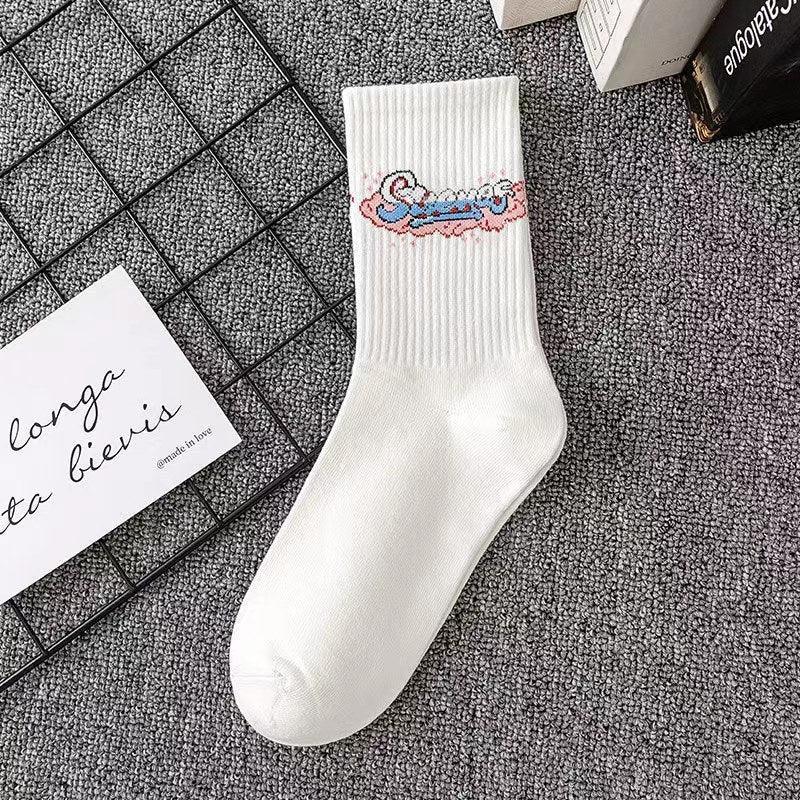 White ribbed cotton crew sock with pastel graphic text design, laid flat on gray carpet.