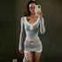 Woman wearing a fitted grey long sleeve top and mini skirt with white lace trim.