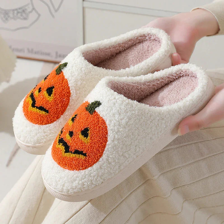 Cozy white fleece slippers with orange pumpkin embroidery, slip-on fit, plush interior.