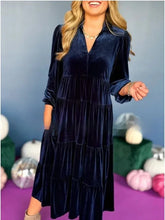 Woman wearing a navy blue velvet tiered midi dress with long sleeves and relaxed fit