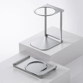 Minimalist silver metal headphone stand with modern geometric design on white display blocks