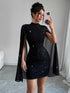 Woman wearing fitted black mini dress with glitter details and sheer cape sleeves