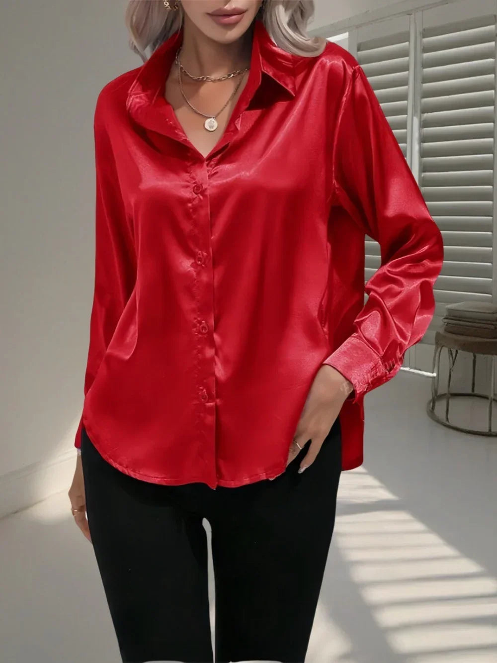 Woman in a loose-fit, long sleeve red satin blouse with black pants, modern minimalist style