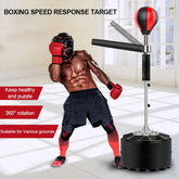 Athletic man in black shorts and red gloves using a boxing reflex trainer indoors
