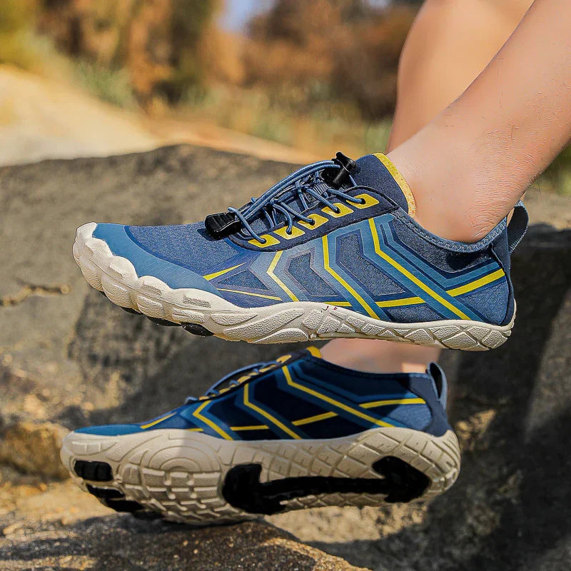 Blue and yellow athletic sneakers with rugged soles, lightweight fit, worn outdoors on rocks