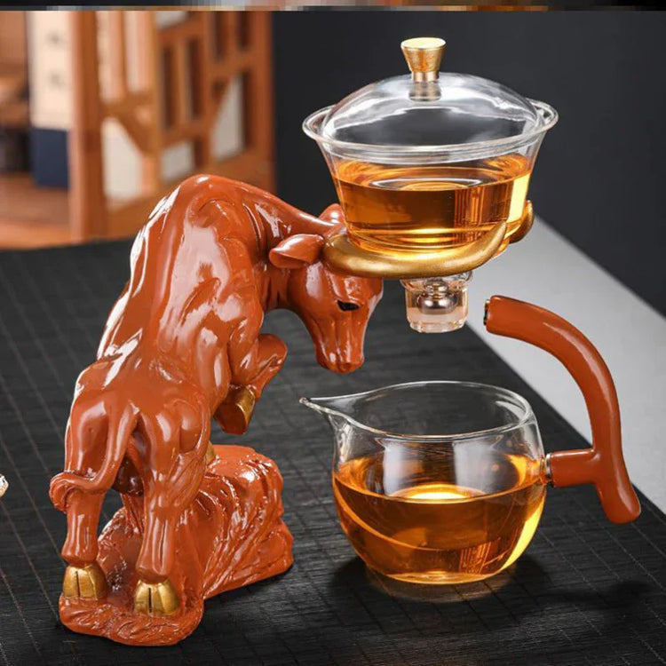 Glass tea set with sculpted bull stand, amber liquid, modern artistic design on black mat
