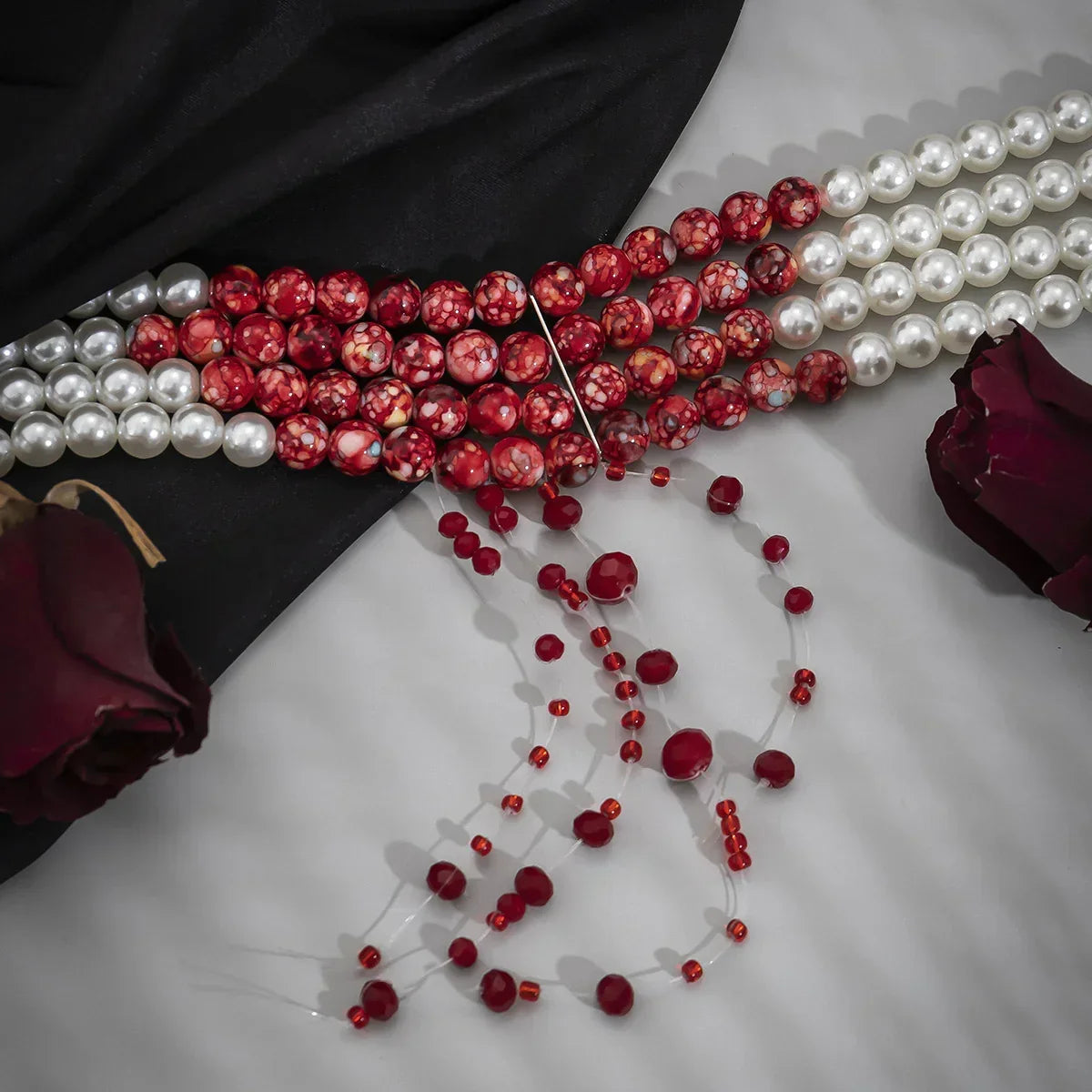 Elegant pearl and red beaded necklace on satin with dark red roses, modern street style jewelry