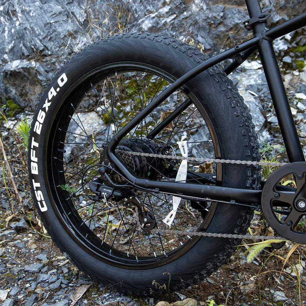 Black fat tire bike with rugged CST BFT 26x4.0 tires and matte frame on rocky terrain