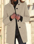 Woman wearing a beige wool blend coat with black buttons, tailored fit, and high collar.