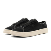 Black suede low-top sneakers with chunky cream rubber soles and lace-up design