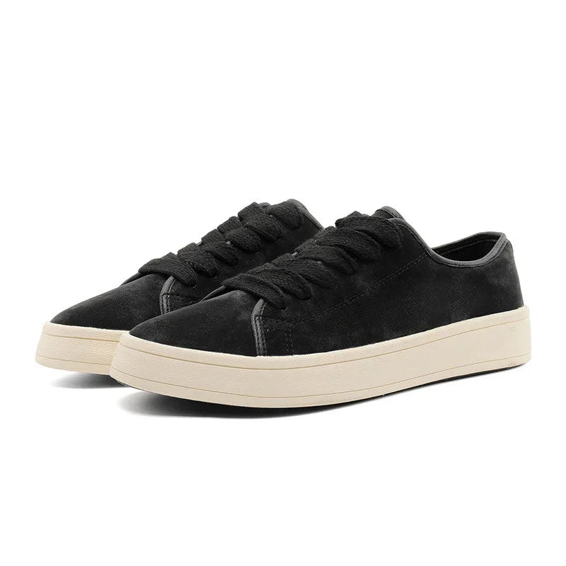 Black suede low-top sneakers with chunky cream rubber soles and lace-up design