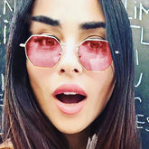 Woman wearing geometric pink tinted sunglasses, straight dark hair, street style look