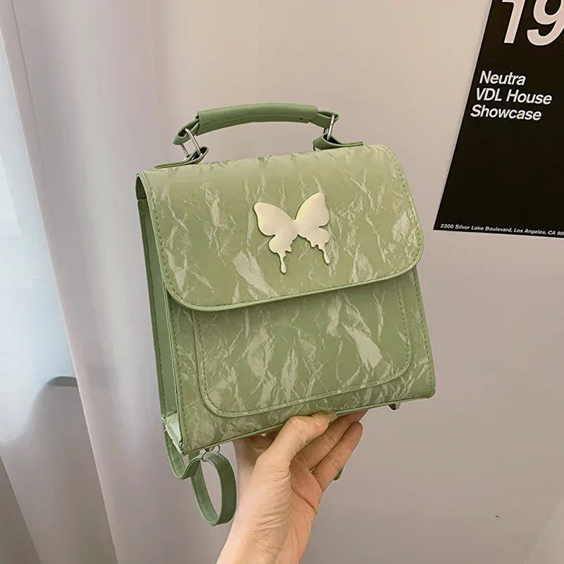 Light green faux leather mini backpack with butterfly appliqué and textured finish