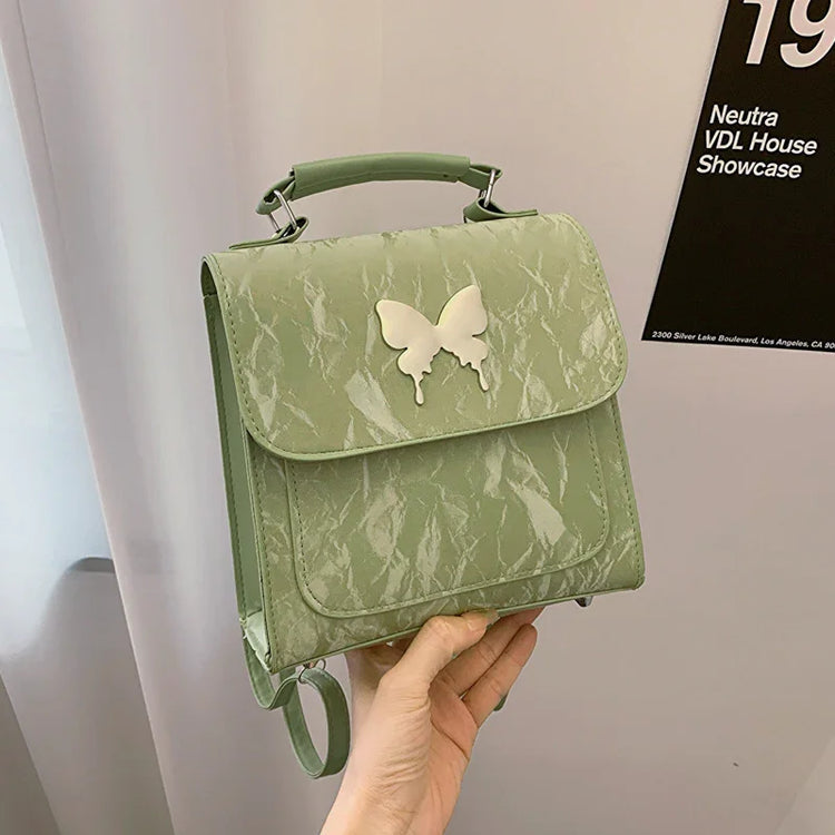 Light green faux leather mini backpack with butterfly appliqué and textured finish